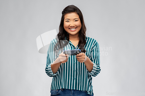 Image of happy asian woman playing video game with gamepad