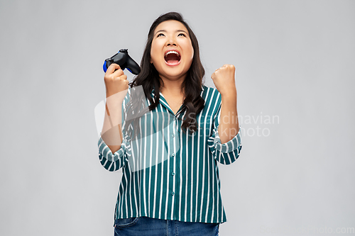 Image of happy asian woman playing video game with gamepad