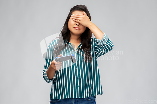 Image of upset asian woman playing video game with gamepad