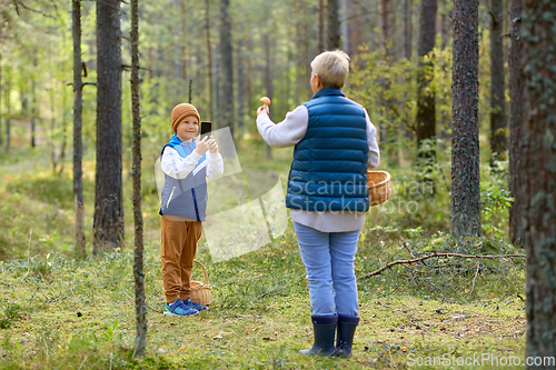 Image of grandson photographing grandmother with mushroom