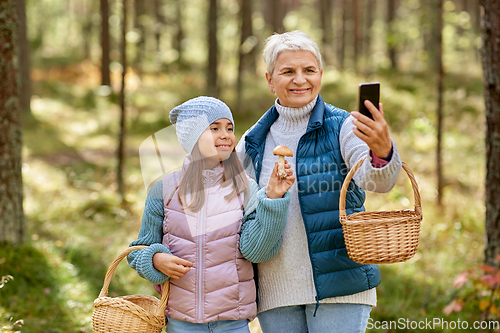 Image of grandma with granddaughter taking selfie in forest