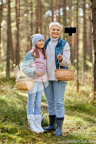 Image of grandma with granddaughter taking selfie in forest