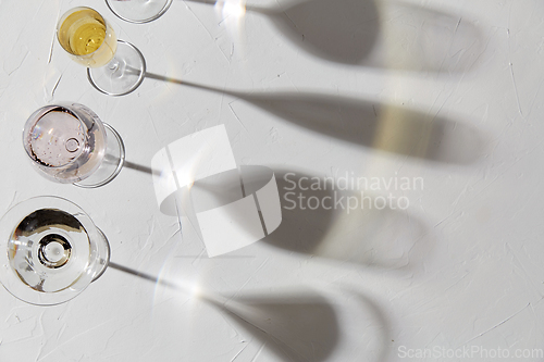 Image of wine glasses dropping shadows on white surface