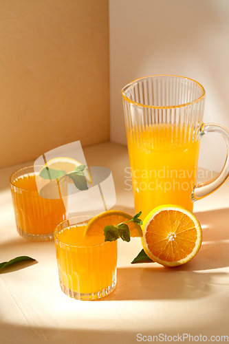 Image of glasses with orange juice and peppermint on table