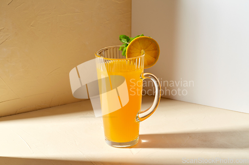 Image of jug with orange juice and peppermint on table