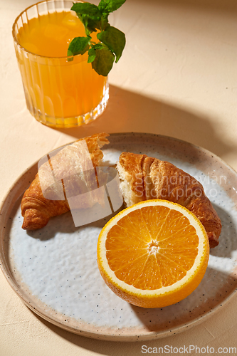 Image of glass of orange juice and croissant on plate