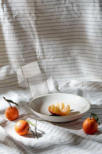 Image of still life with mandarins on plate over drapery