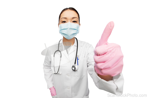 Image of asian female doctor in mask showing thumbs up