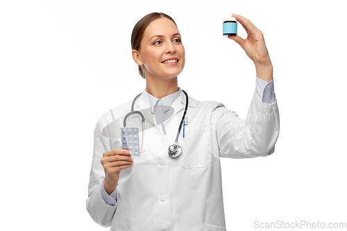 Image of smiling female doctor holding medicine pills