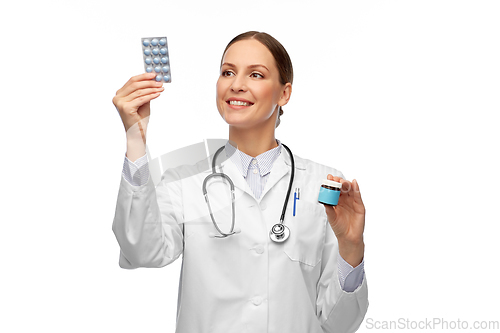 Image of smiling female doctor holding medicine pills