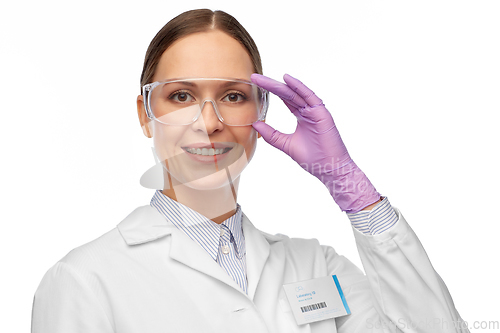 Image of smiling female scientist in goggles and gloves