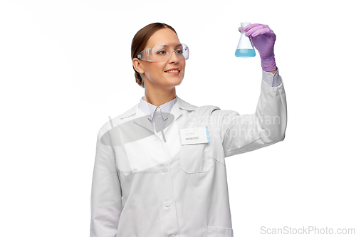 Image of female scientist in goggles with chemical in flask