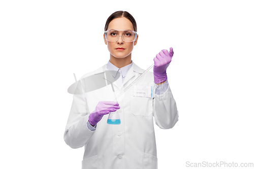 Image of female scientist in goggles with chemical in flask