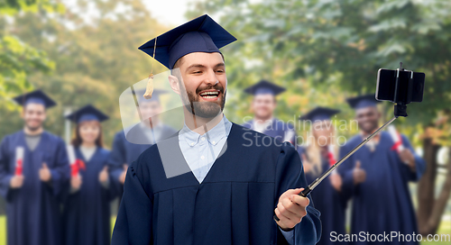 Image of male graduate student with smartphone takes selfie