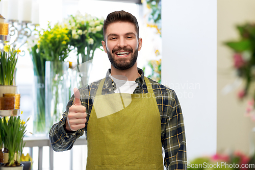 Image of happy male seller showing thumbs up at flower shop