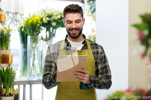 Image of happy male seller with clipboard at flower shop