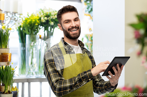 Image of happy male seller with tablet pc at flower shop