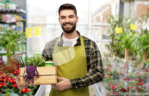 Image of happy man with box of tools at garden center