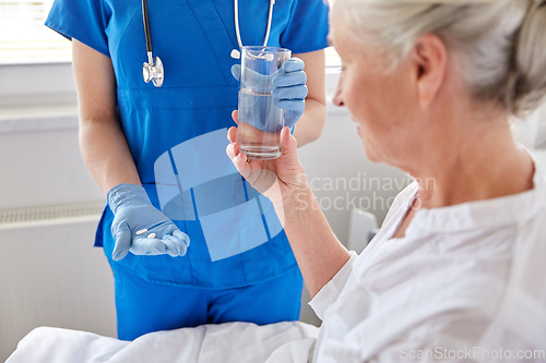 Image of nurse giving medicine to senior woman at hospital