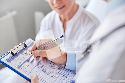 Image of senior woman and doctor with clipboard at hospital