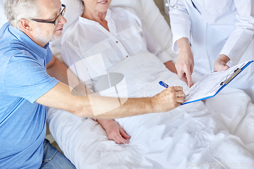 Image of old couple and doctor with clipboard at hospital