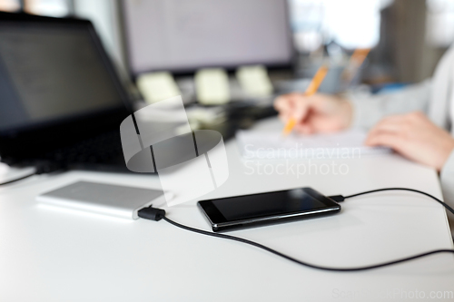 Image of smartphone with powerbank on table at office