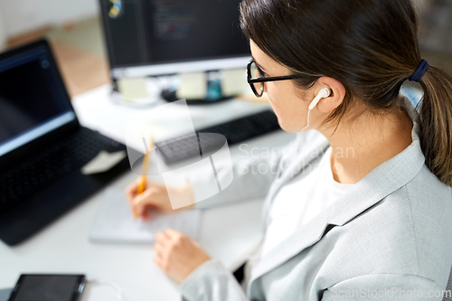 Image of businesswoman with earphones working at office