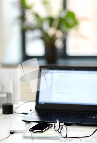 Image of laptop, smartphone and notebook on table at office