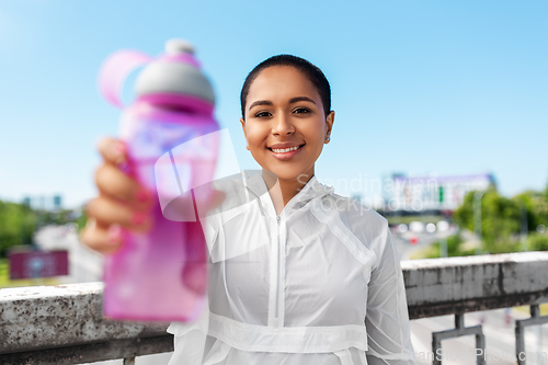 Image of african american woman drinking water from bottle