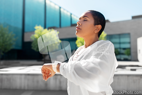 Image of young woman with smart watch breathing outdoors