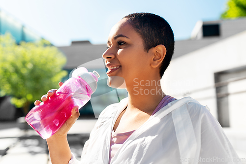 Image of african american woman drinking water from bottle