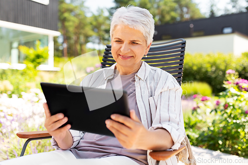 Image of happy senior woman with tablet pc at summer garden