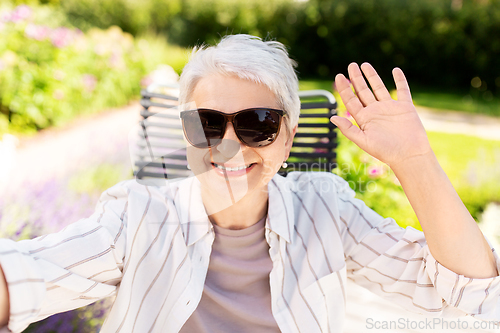 Image of happy senior woman taking selfie at summer garden