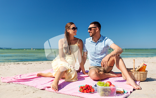 Image of happy couple having picnic on summer beach