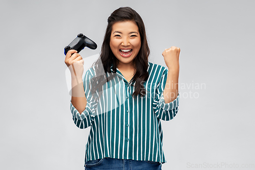 Image of happy asian woman playing video game with gamepad