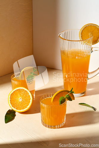 Image of glasses with orange juice and peppermint on table