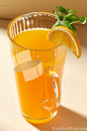 Image of jug with orange juice and peppermint on table