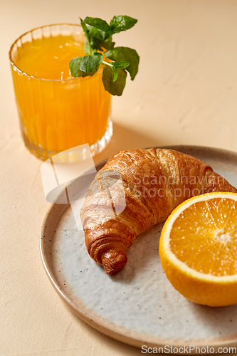 Image of glass of orange juice and croissant on plate