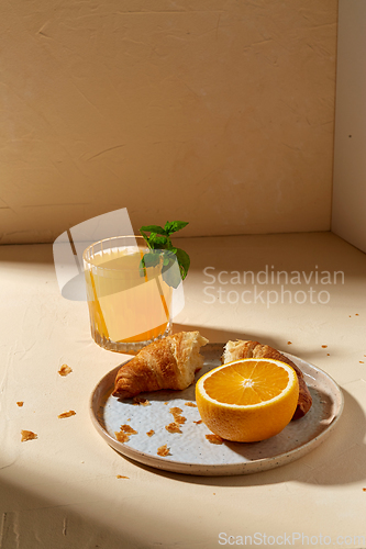 Image of glass of orange juice and croissant on plate