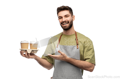 Image of happy smiling barman in apron with takeaway coffee