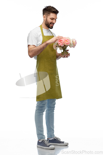 Image of happy smiling male gardener with flowers in vase