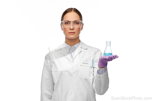 Image of female scientist in goggles with chemical in flask