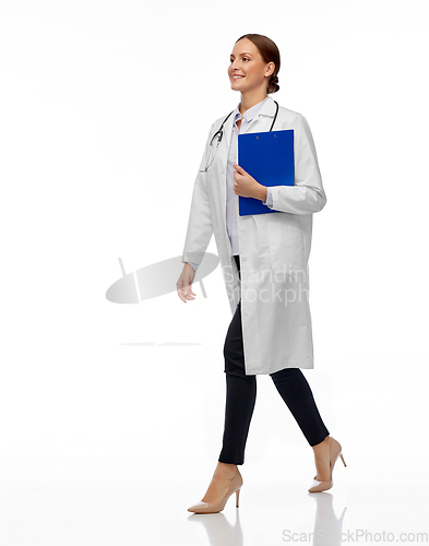 Image of happy smiling female doctor walking with clipboard
