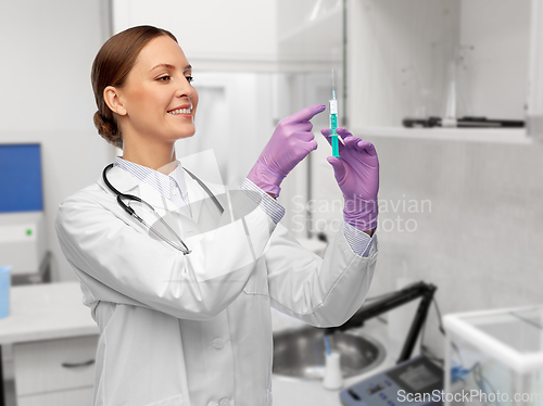 Image of happy female doctor with syringe at hospital