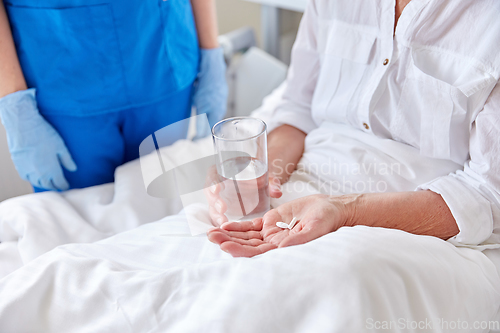 Image of nurse giving medicine to senior woman at hospital