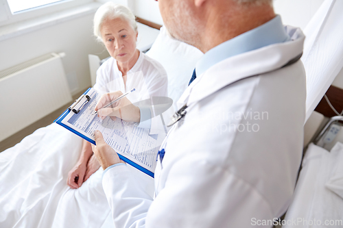 Image of senior woman and doctor with clipboard at hospital