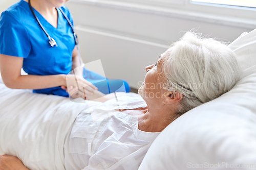 Image of doctor or nurse visiting senior woman at hospital