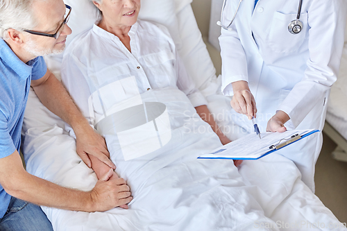 Image of old couple and doctor with clipboard at hospital