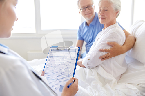 Image of old couple and doctor with clipboard at hospital