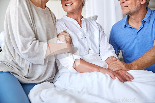 Image of happy family visiting senior woman at hospital